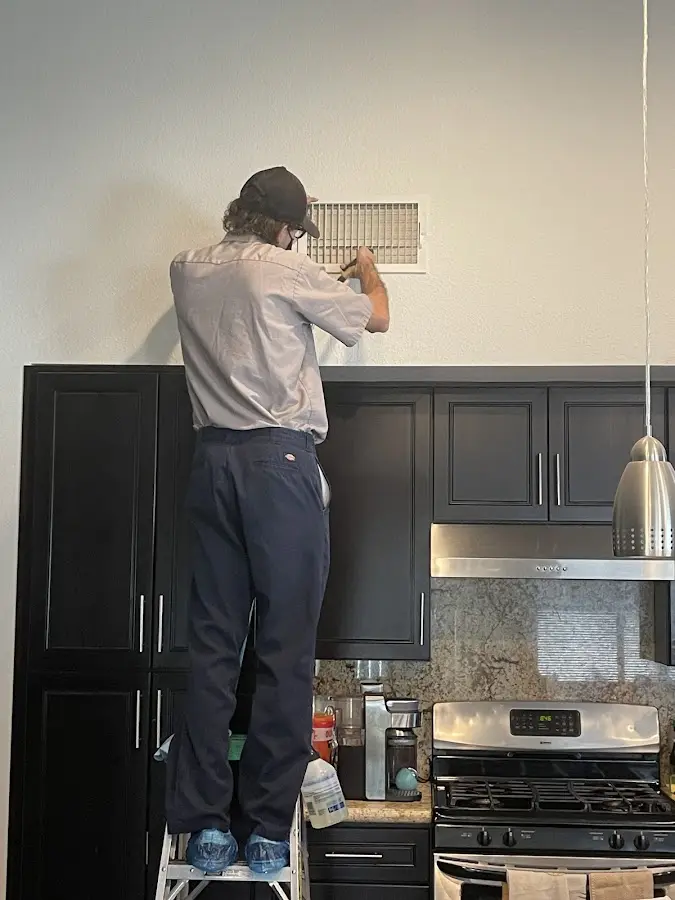Technician inspecting an air vent during HVAC service in Waikele